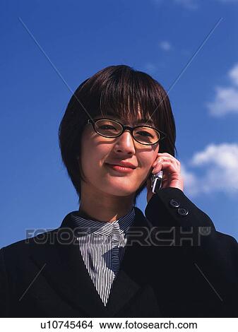 Picture - Businesswoman using a mobile phone under the blue sky, low angle view, portrait. Fotosearch