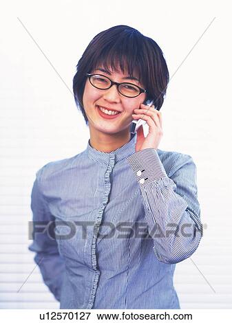 Stock Photo - Businesswoman using a mobile phone, smiling, front view, portrait. Fotosearch