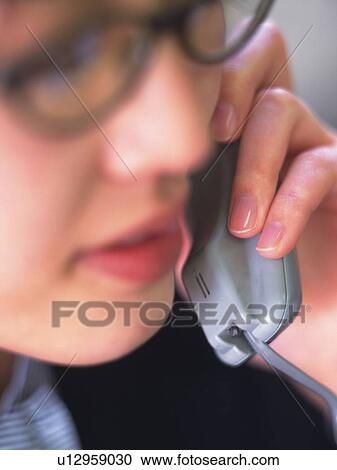 Stock Image - Businesswoman using a phone, close up, soft focus. Fotosearch