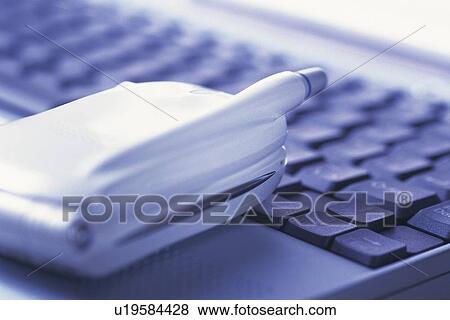 Stock Photo - Folded mobile phone put on laptop, high angle view, close up. Fotosearch