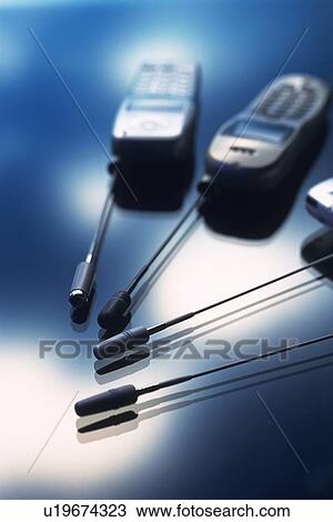 Stock Image - Four antennas of mobile phones reaching to each other, high angle view, soft focus. Fotosearch