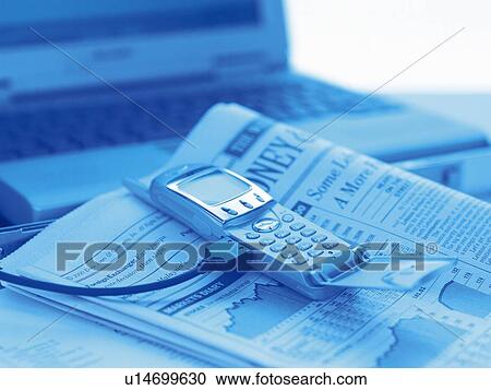 Stock Image - Mobile phone being connected to laptop, high angle view, toned image. Fotosearch