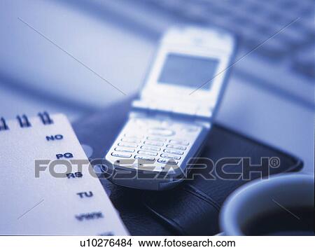 Picture - Mobile phone put on personal organizer, high angle view, close up, toned image. Fotosearch
