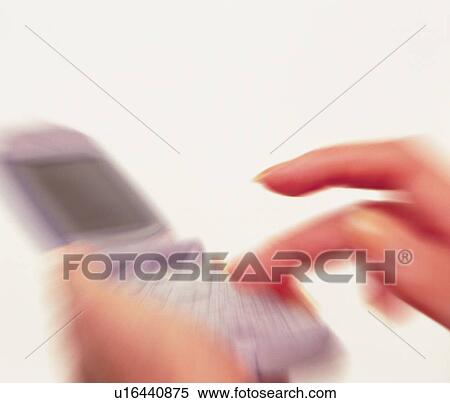 Stock Photography - Woman holding a mobile phone and pushing buttons, high angle view, close up, blurred motion. Fotosearch