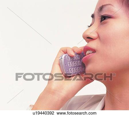 Stock Image - Woman using a mobile phone, side view. Fotosearch
