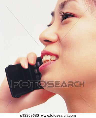 Woman using a mobile phone, smiling, side view, close up View Large Photo Image Stock Image - Woman using a mobile phone, smiling, side view, close up. Fotosearch