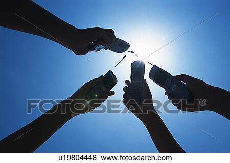 Four People Holding a Mobile Phone, Low Angle View View Large Photo Image Stock Photo - Four People Holding a Mobile Phone, Low Angle View. Fotosearch