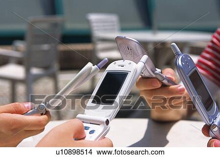 Picture - Four People Holding a Mobile Phone, Side View. Fotosearch