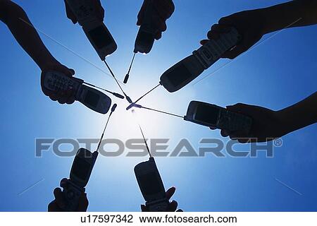 Stock Image - Seven People Holding a Mobile Phone, Low Angle View, Silhouette. Fotosearch