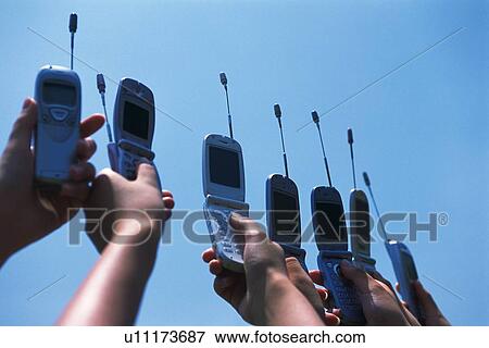 Stock Photo - Seven People Holding a Mobile Phone, Low Angle View. Fotosearch