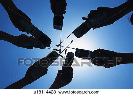 Stock Photo - Seven People Holding a Mobile Phone, Low Angle View, Silhouette. Fotosearch