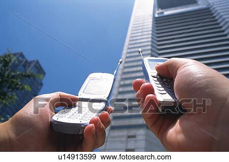 Two People Holding a Mobile Phone, Low Angle View View Large Photo Image Stock Photo - Two People Holding a Mobile Phone, Low Angle View. Fotosearch