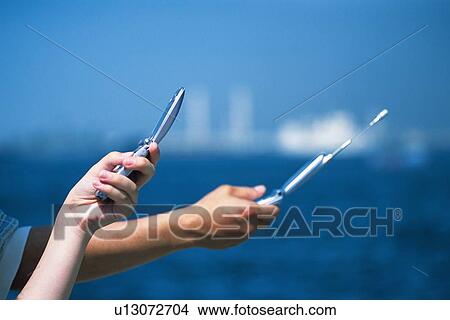 Two People Holding a Mobile Phone, Side View View Large Photo Image Picture - Two People Holding a Mobile Phone, Side View. Fotosearch