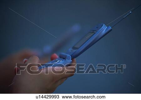 Stock Image - Two People Holding a Mobile Phone, Side View. Fotosearch