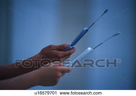 Stock Image - Two People Holding a Mobile Phone, Side View. Fotosearch