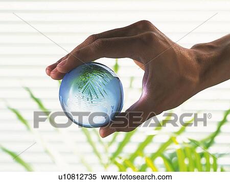 Stock Photography - Hand grabbing a glass made globe, Close Up. Fotosearch