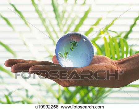 Stock Photograph - Hand holding a glass made globe, Close Up. Fotosearch