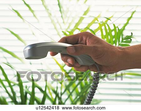 Stock Photo - Hand holding a handset face down, Side View. Fotosearch