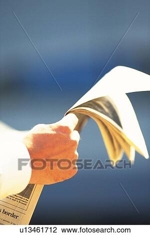 Stock Image - Hand holding news paper, Rear View. Fotosearch