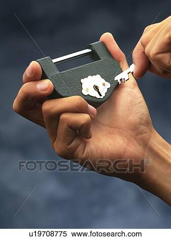 Stock Photography - Hand unlocking a padlock with a key, Close Up. Fotosearch