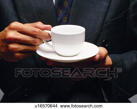 Picture - Hands holding a tea cup and a saucer, Front View. Fotosearch