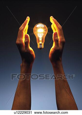 Stock Image - Light bulb floating between hands, Front View. Fotosearch