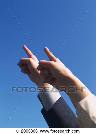 Stock Image - Two hands pointing up the sky, Low Angle View. Fotosearch