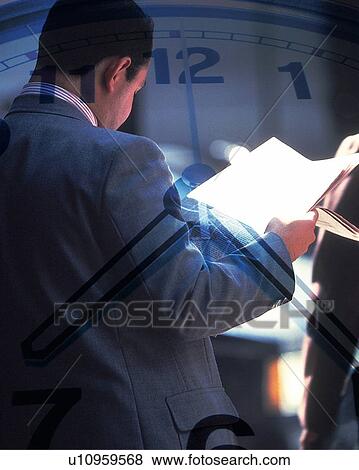 Stock Photo - Businessman holding folded newspaper and image of clock, CG, composition, rear view. Fotosearch