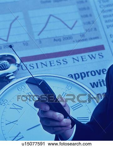 Stock Image - Businessman holding mobile phone with image of clock and financial press, CG, composition, toned image. Fotosearch