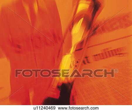 Stock Photo - Businessman with image of hourglass and newspaper, CG, composition, blurred motion, toned image. Fotosearch