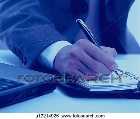 Stock Photograph - Businessman writing down on personal organizer, toned image. Fotosearch