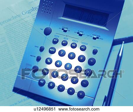 Stock Image - Calculator on newspaper, close up, toned image, high angle view. Fotosearch