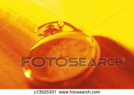 Stock Image - Clock on newspaper, soft focus, toned image, high angle view, close up. Fotosearch