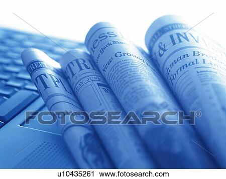 Stock Image - Folded newspapers and laptop, high angle view, close up, toned image. Fotosearch