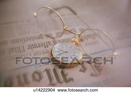 Glasses and clock on newspaper, high angle view, close up, soft focus View Large Photo Image Picture - Glasses and clock on newspaper, high angle view, close up, soft focus. Fotosearch