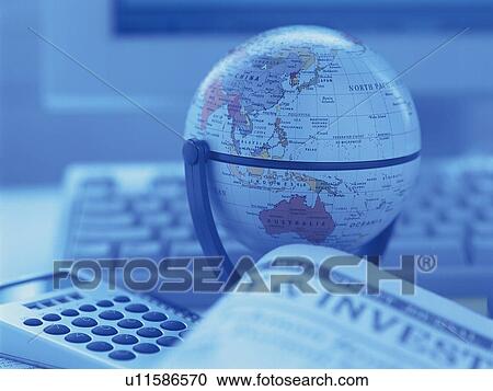 Stock Image - Globe, calculator, financial press and personal computer on desk, close up, soft focus, toned image. Fotosearch