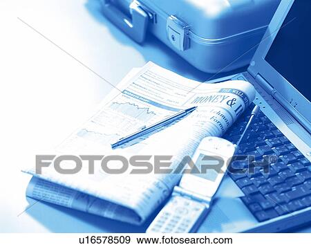 Stock Photo - Newspaper and mobile phone on laptop, business trip, high angle view, toned image. Fotosearch