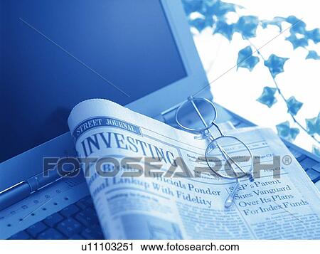 Stock Image - Newspaper on laptop, high angle view, close up, toned image. Fotosearch