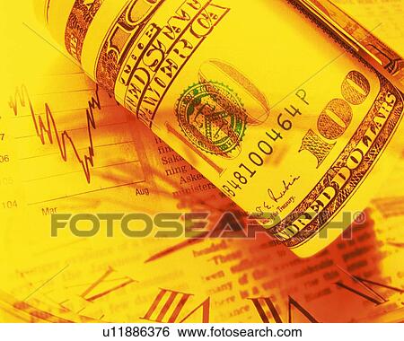 Stock Photograph - Rolled up US banknotes with image of clock and newspaper, toned image, high angle view, close up. Fotosearch