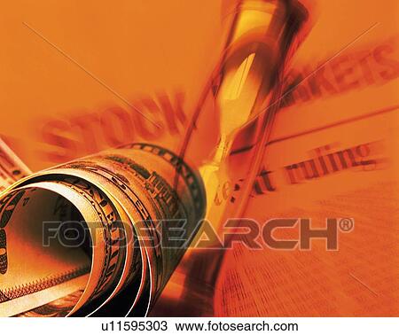 Stock Image - Rolled US banknotes with image of hourglass and newspaper, CG, composition, blurred motion, toned image. Fotosearch