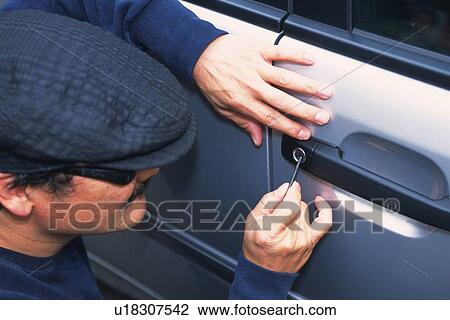 Stock Image - Burglar breaking into a car, High Angle View. Fotosearch