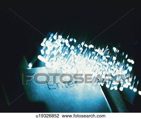 Stock Image - Bunch of illuminated fiber optics on computer keyboard, close up, high angle view. Fotosearch