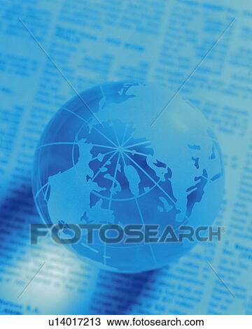 Stock Image - Globe on newspaper, high angle view, close up, soft focus, toned image. Fotosearch