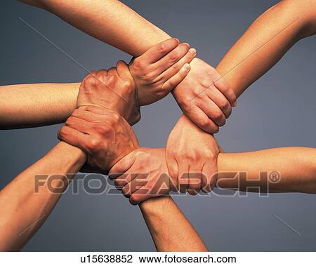 Stock Image - Three people holding arms in circle, high angle view. Fotosearch