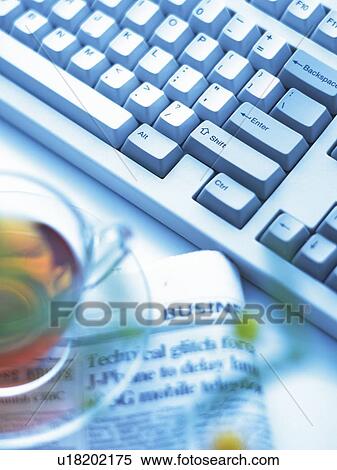 Stock Photography - Keyboard, Newspaper and Tea on the Desk, Close Up. Fotosearch