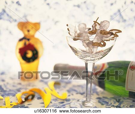 Stock Photograph - Angels in glass with teddy bear and champagne bottle, front view. Fotosearch
