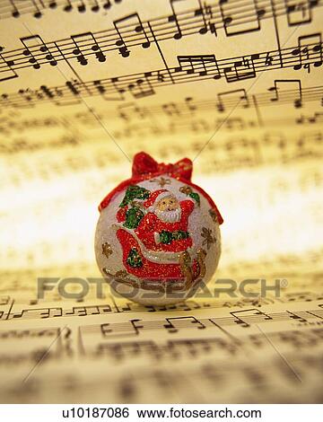 Stock Photograph - Ball with paint of Santa Claus on sheet music, front view. Fotosearch