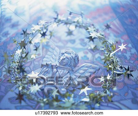 Stock Image - Christmas wreath around angel ornament, high angle view, toned image. Fotosearch