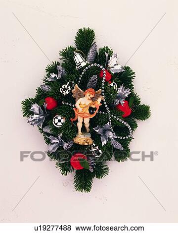 Stock Photo - Christmas wreath with angel figurine, front view, white background. Fotosearch