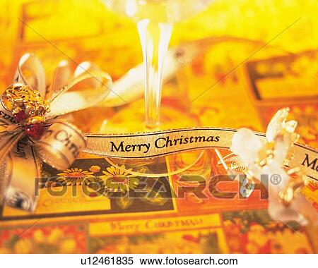 Glass and angel figurine with ribbons printed "Merry Christmas", high angle view View Large Photo Image Stock Photography - Glass and angel figurine with ribbons printed "Merry Christmas", high angle view. Fotosearch